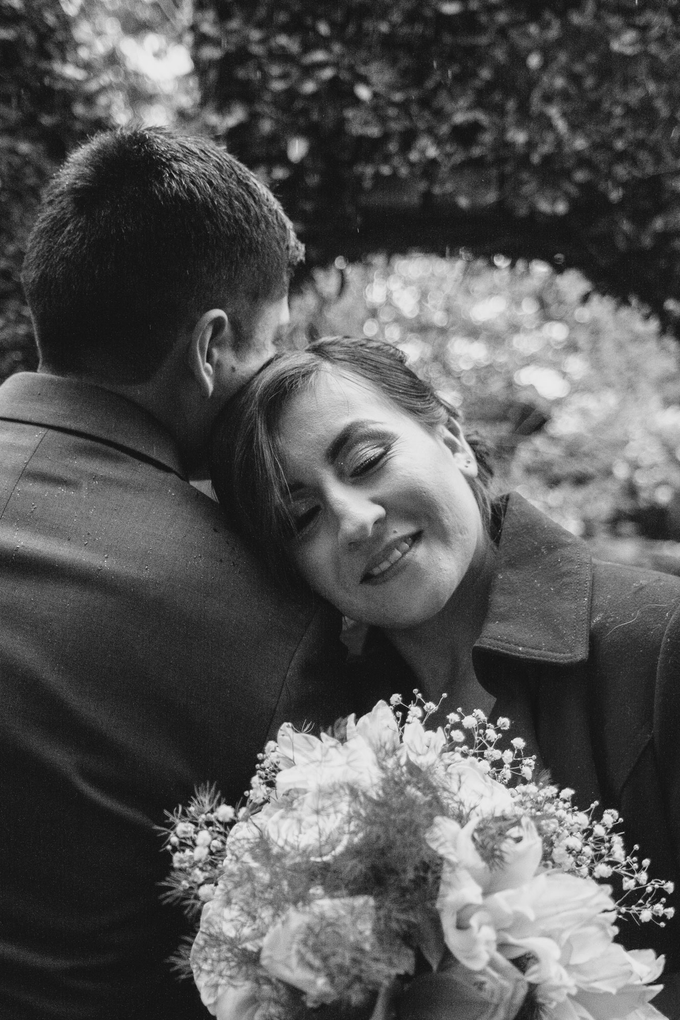 Black-and-white photograph of Karla leaning against Birhon with her bouquet.